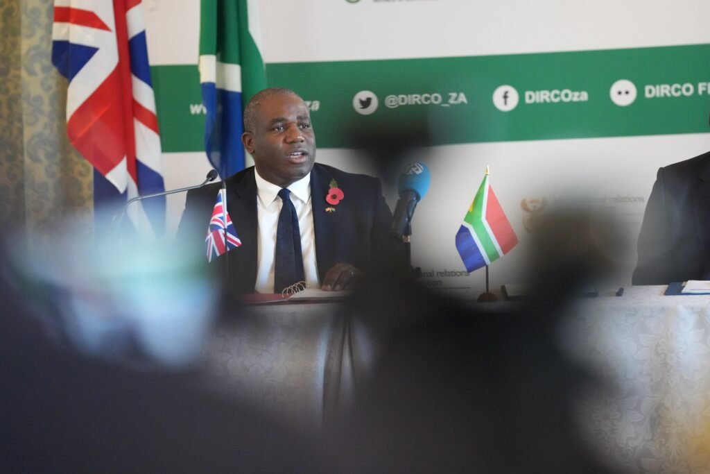 The UK Foreign Secretary speaks at a press conference alongside South African flags.
