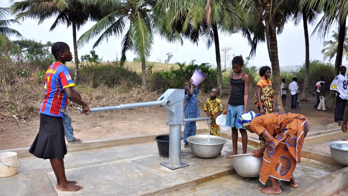 Women and children collecting water at a village hand pump in West Africa.