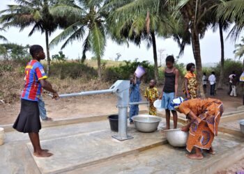 Women and children collecting water at a village hand pump in West Africa.