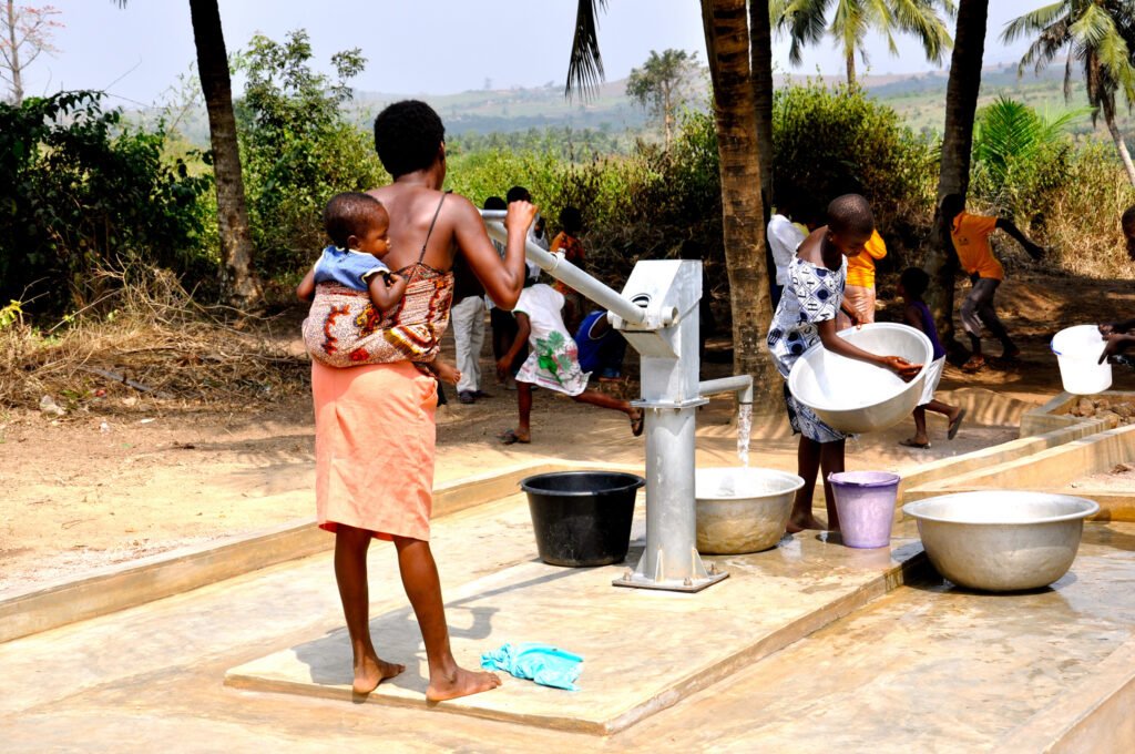 Women and children collecting water at a village hand pump in West Africa.