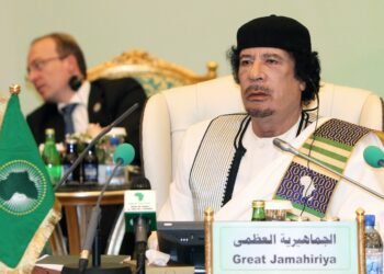 Muammar Gaddafi seated beneath an African Union flag in 2010.