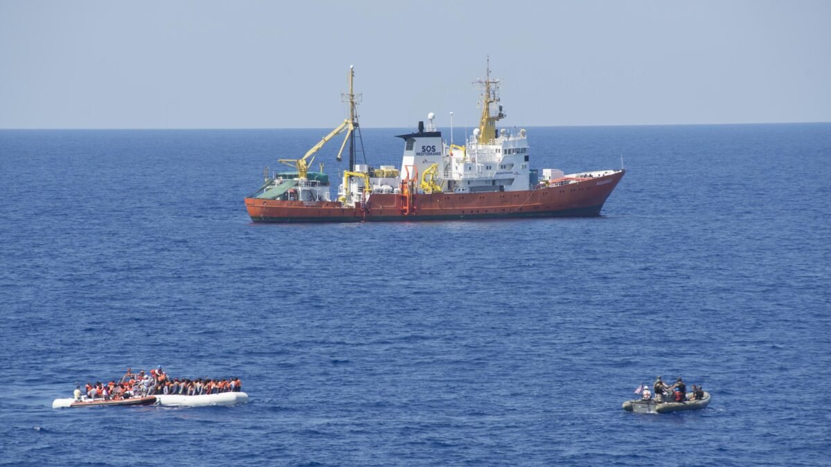 An overloaded migrant boat alongside a naval vessel in the Mediterranean.