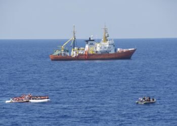 An overloaded migrant boat alongside a naval vessel in the Mediterranean.