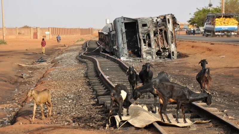 The burnt-out wreck of a fuel tanker lying beside a railway line on a main road in Niamey, Niger.