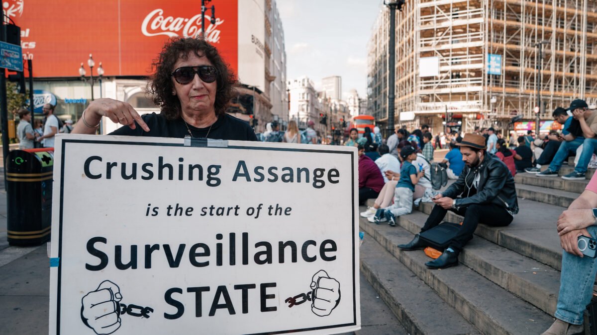 A demonstrator at Piccadilly Circus, London, holding a placard reading Crushing Assange is the start of the Surveillance State.