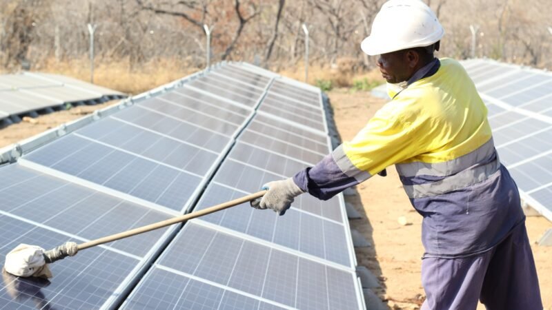 A technician cleaning a solar panel array.