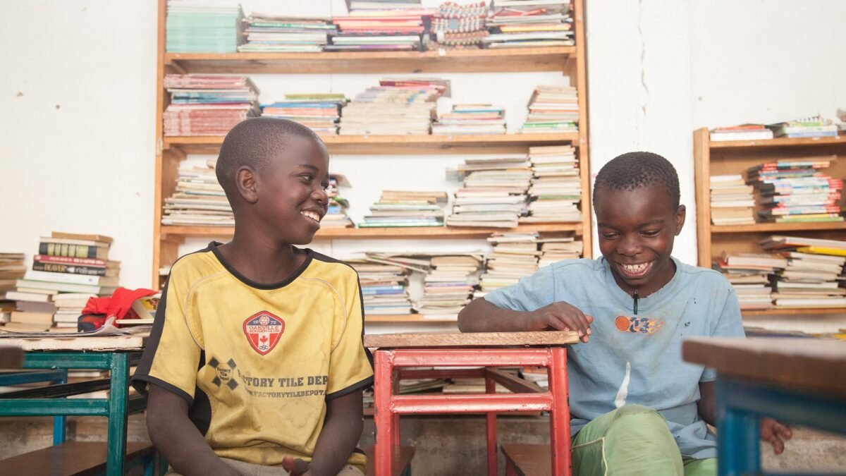 Two boys reading and laughing in a library in Zambia.