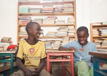 Two boys reading and laughing in a library in Zambia.