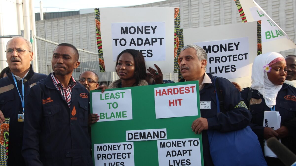 Campaigners at COP21 holding placards demanding adaptation and loss and damage finance for Africa.