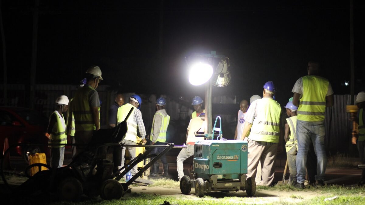 A road construction crew working under floodlights at night in Africa.