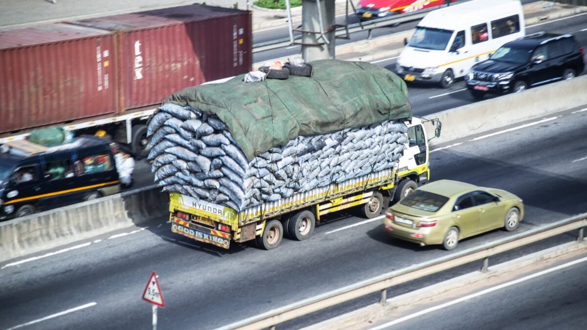 A heavily laden cargo truck in traffic on an urban highway in Ghana.